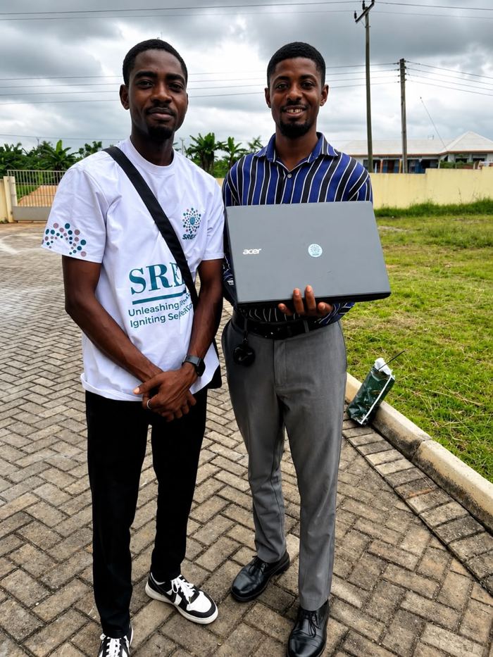 SREF staff presenting a donated laptop to a beneficiary in Ghana