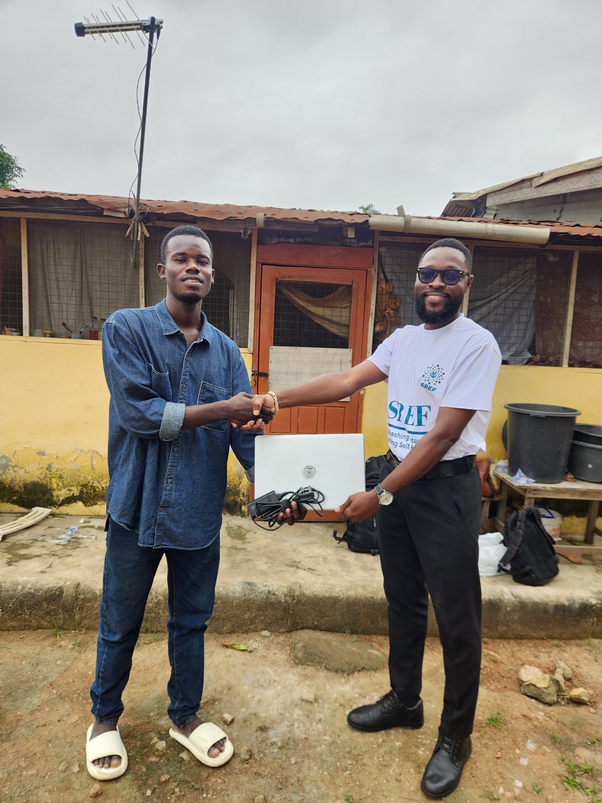 A laptop being handed to an SREF beneficiary
